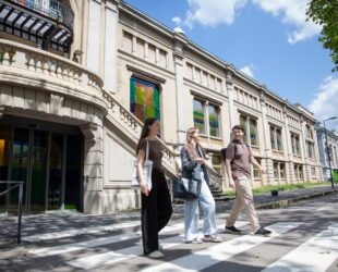 Trois étudiants marchant devant le bâtiment historique de l’ISTP, en sortie de campus, par une journée ensoleillée