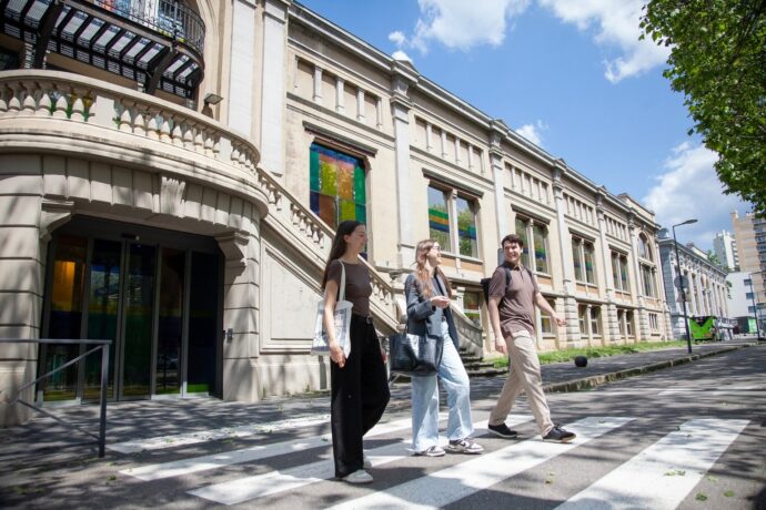 Trois étudiants marchant devant le bâtiment historique de l’ISTP, en sortie de campus, par une journée ensoleillée