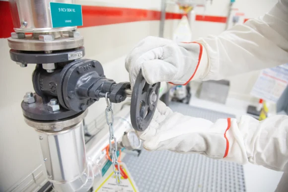 Opérateur avec des gants de protection manipulant une vanne industrielle lors d'une formation en ingénierie nucléaire à l'ISTP